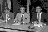 Jean-Paul Champagne et deux hommes à une table de conférence