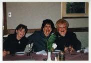 Trois femmes souriantes assises à une table durant un repas.