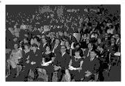 Vue sur la foule (composée d'hommes et de femmes) assise sur des chaises dans l'attente d'un spectacle.