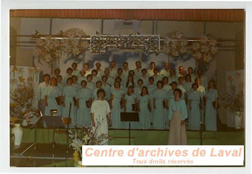 Groupe de personnes sur une scne et faisant partie d'une chorale et habilles d'un uniforme turquoise.