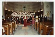Chorale et groupe de violonistes, en compagnie d'une chef d'orchestre dans le coeur d'une église.