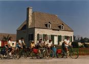 Participants d'une journée cyclo-historique sur leur vélo devant une maison ancestrale. [1983]