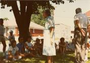 Journée cyclo-historique trajet ouest. Une dizaine de participants assis dans le gazon sous un arbre devant une maison. (22 juillet 1984)