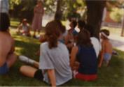 Journée cyclo-historique trajet ouest. Photo floue d'une dizaine de participants assis dans le gazon sous un arbre. (22 juillet 1984).