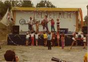 Rallye familial de vélo au Centre de la Nature. Cinq clowns sur scène jouant de la musique devant un jeune public. (Août 1984)
