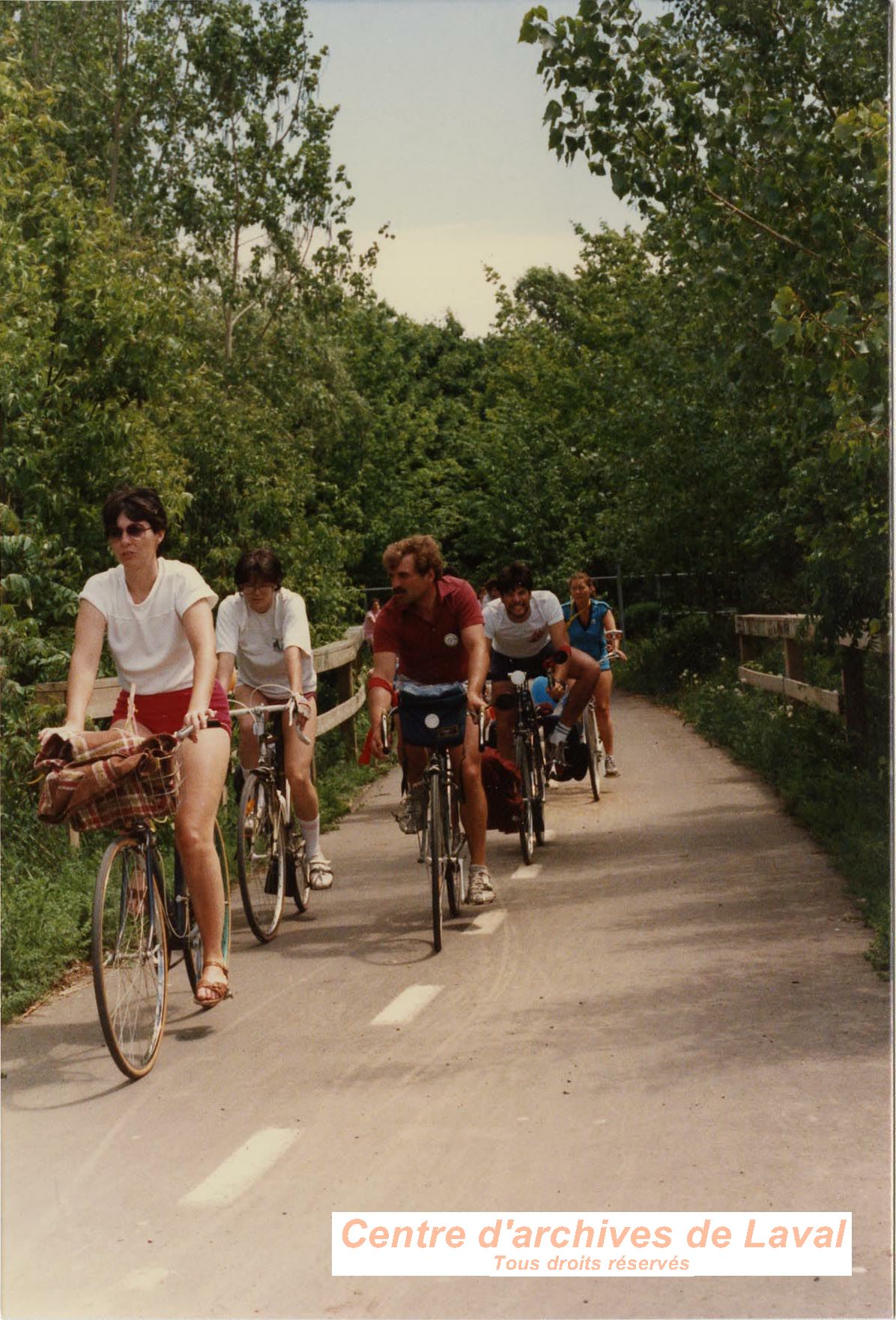 Randonne cycliste. Une dizaine de participants sur leur vlo sur une piste cyclable en fort. [1987]