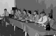 Jean-Guy Rodrigue, Michel Leduc, Jean-Paul Champagne et Bernard Landry assis à une table, en présence de personnes non identifiées