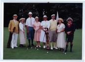 Huit personnes non identifiées posent avec leurs bâtons de golf