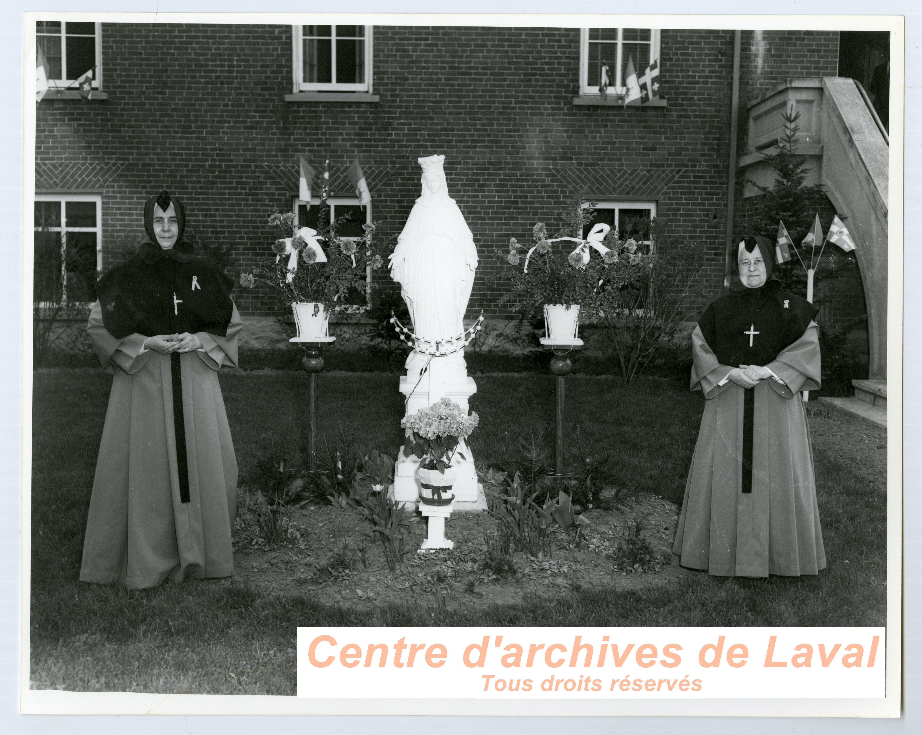 Deux religieuses devant une statue de la Vierge Marie lors des clbrations du 100e anniversaire du couvent d'Youville (1854-1954)  Saint-Benot en 1954.