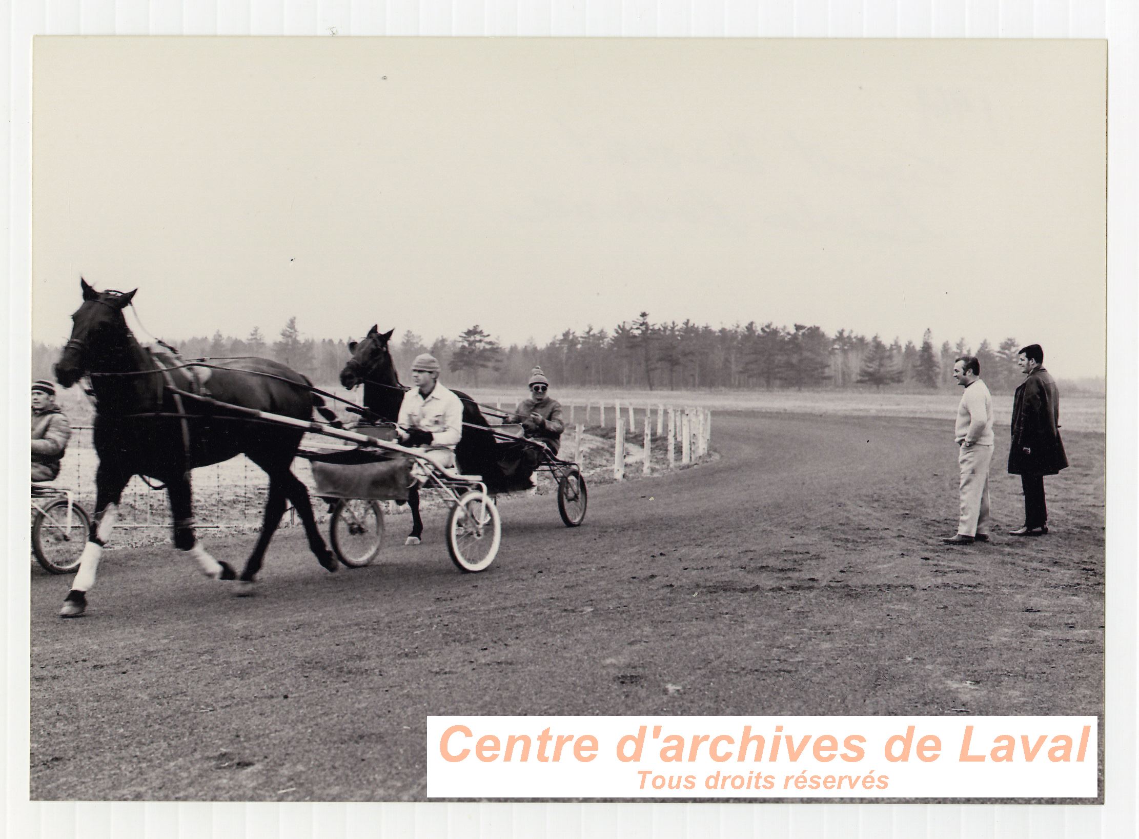 Gilles Lachance (debout,  gauche) regardant une pratique de courses de chevaux  son curie  Saint-Benot en 1969.