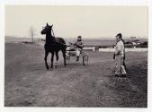 Gilles Lachance (debout,  gauche) regardant une pratique de courses de chevaux  son curie  Saint-Benot en 1969.