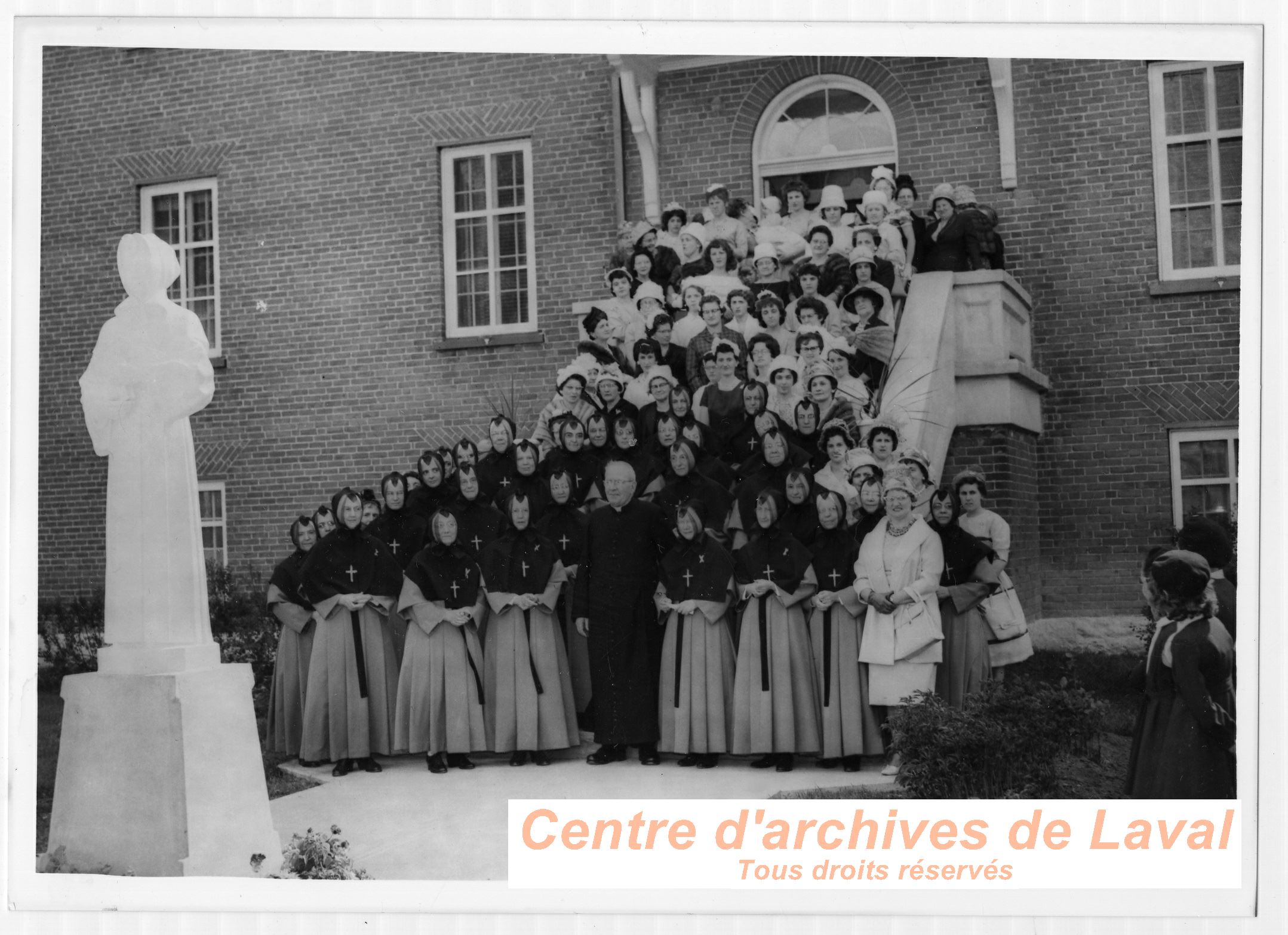 Le cur Ernest Vaillancourt, des religieuses et des femmes runies devant le couvent d'Youville  Saint-Benot lors d'un vnement.