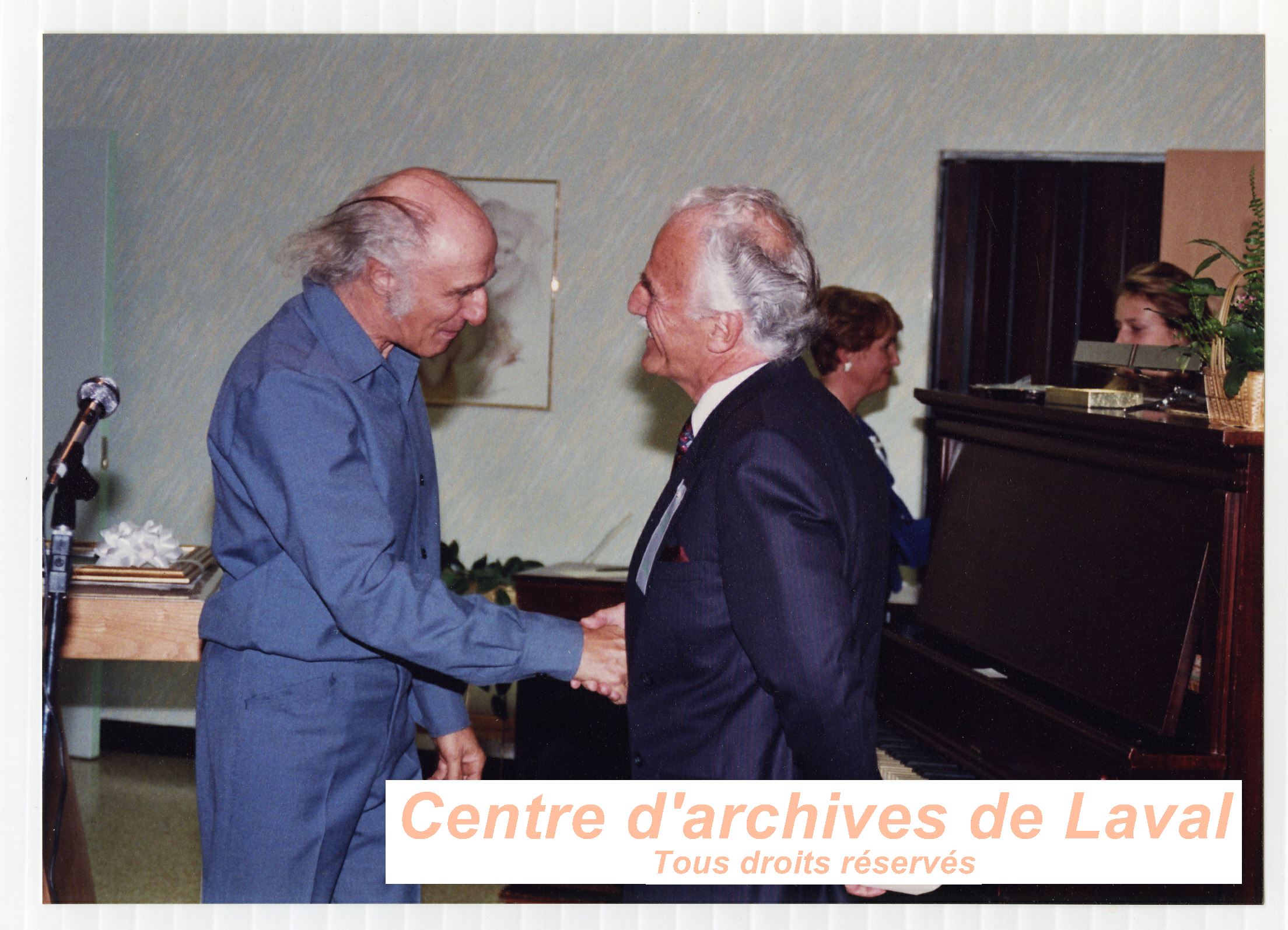 Gilles Vigneault serrant la main du Dr. Augustin Roux lors du 10e anniversaire du Centre d'accueil Saint-Benot en 1989.