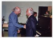 Gilles Vigneault serrant la main du Dr. Augustin Roux lors du 10e anniversaire du Centre d'accueil Saint-Benot en 1989.