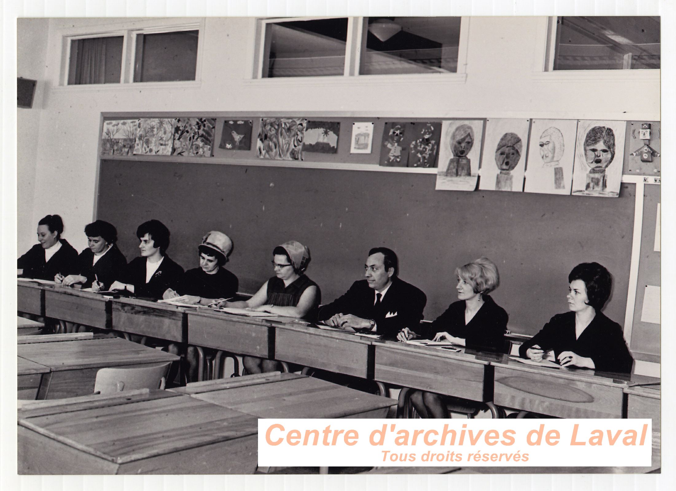 Groupe d'adultes assis  des pupitres  l'cole Girouard de Saint-Benot en 1968.