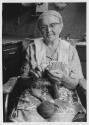 Femme tricotant dans sa cuisine, à Sainte-Scholastique