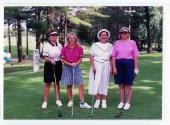 Quatre personnes non identifiées posent avec leurs bâtons de golf