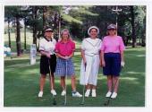 Quatre personnes non identifiées posent avec leurs bâtons de golf