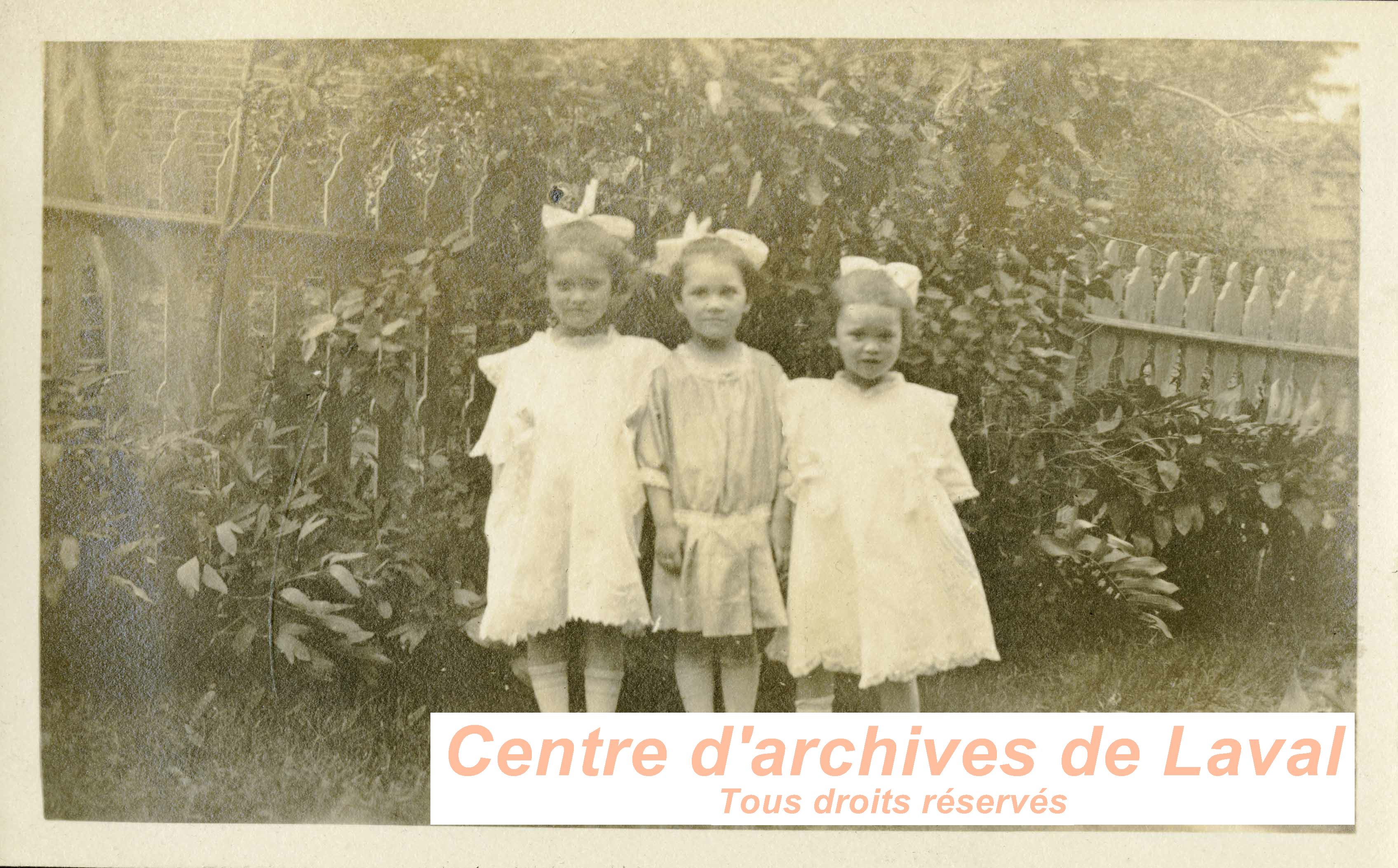 Trois fillettes dans un jardin.