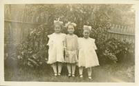 Trois fillettes dans un jardin.
